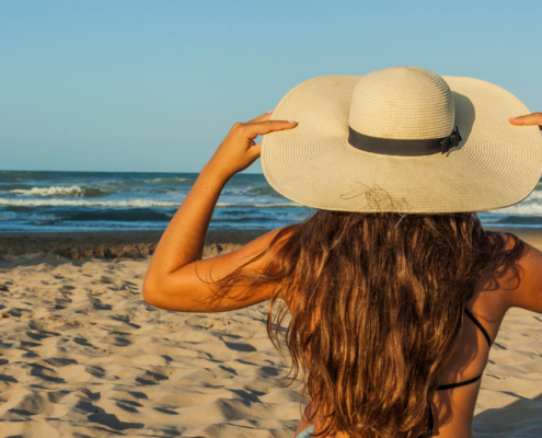 A young woman wearing a big, floopy hat at the beach